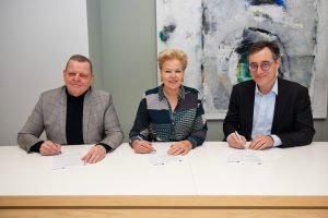 Drie mensen ondertekenen documenten aan een witte tafel bij een samenwerking tussen Catharina Ziekenhuis en VGZ.
