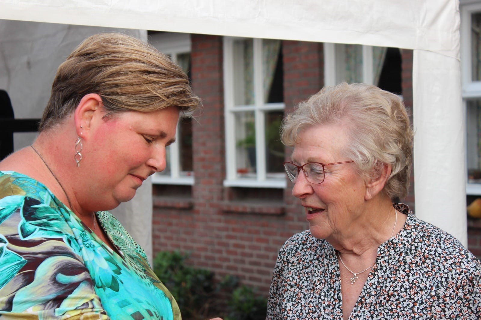 Twee vrouwen staan buiten bij een bakstenen gebouw en praten over longkanker en de keuzehulp voor betere besluitvorming.