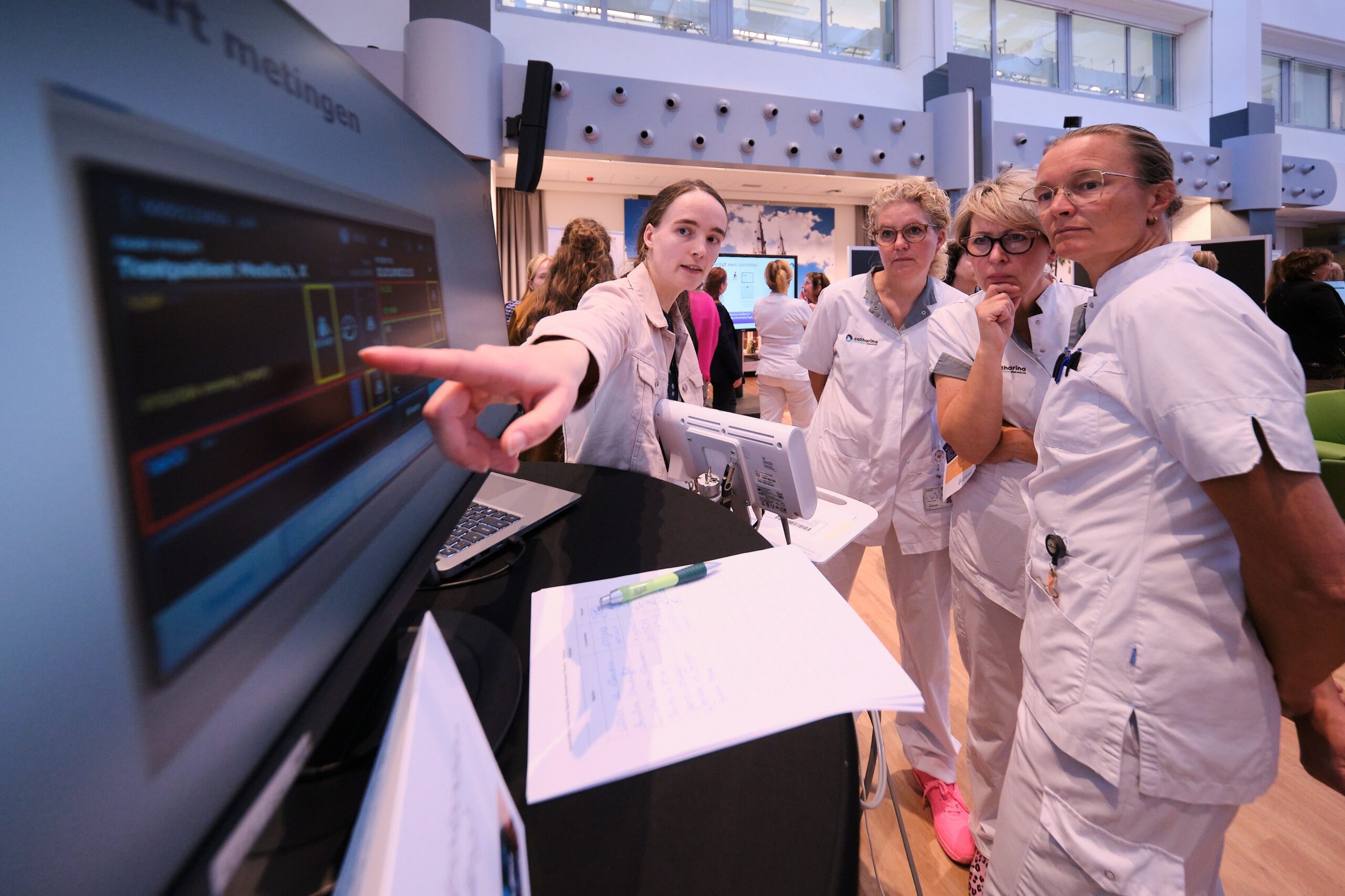 Vier zorgverleners in witte uniformen overleggen bij een monitor en papieren in het Catharina Ziekenhuis.